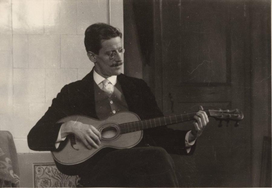 James Joyce seated, playing guitar, Zurich, 1915